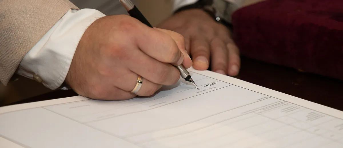 Ruka s plnicím perem podepisuje formulář