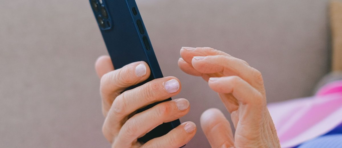 Ruce seniorky drží chytrý telefon