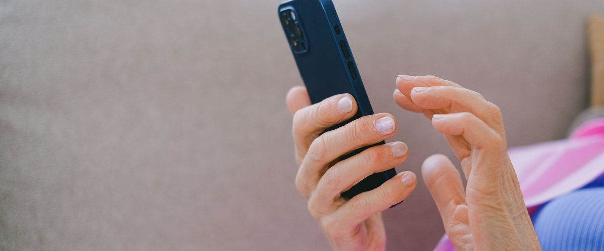 Ruce starší ženy drží chytrý telefon