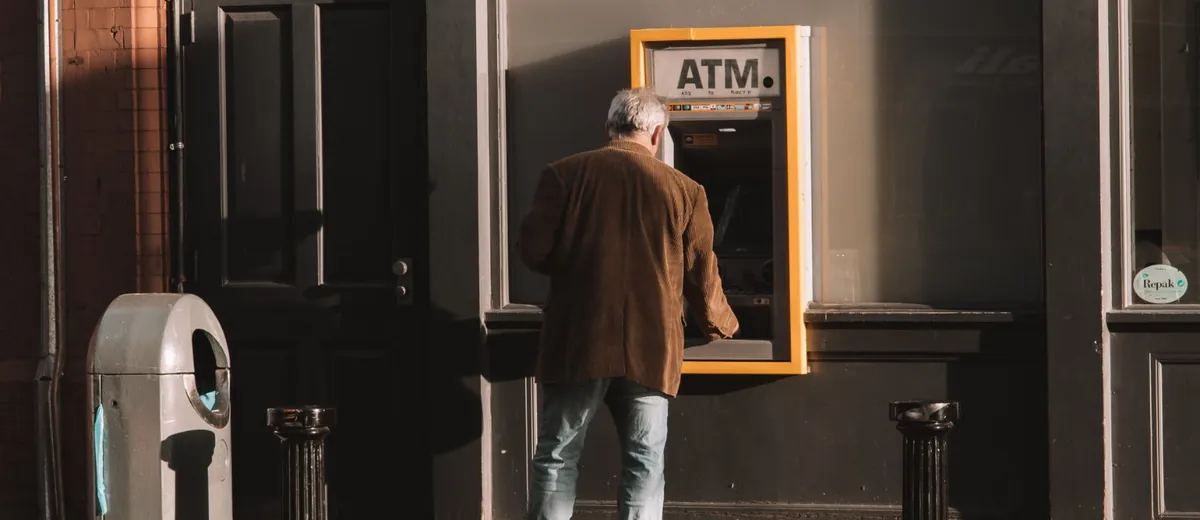 Starší muž vybírá peníze z bankomatu na ulici
