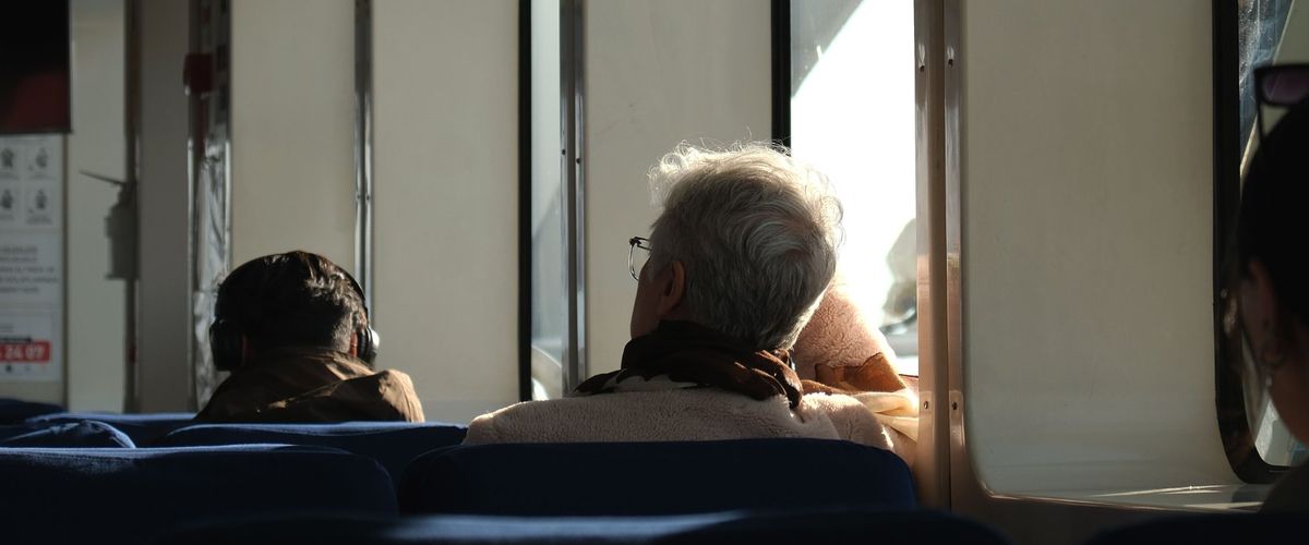 Senior se dívá z okna při cestě veřejnou dopravou